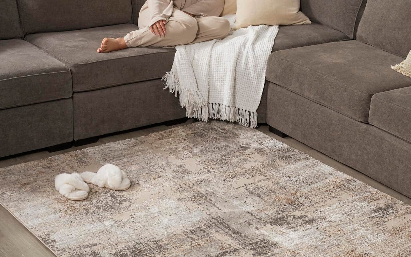 An area rug lies on the floor in front of a couch An area rug lies on the floor in front of a couch
