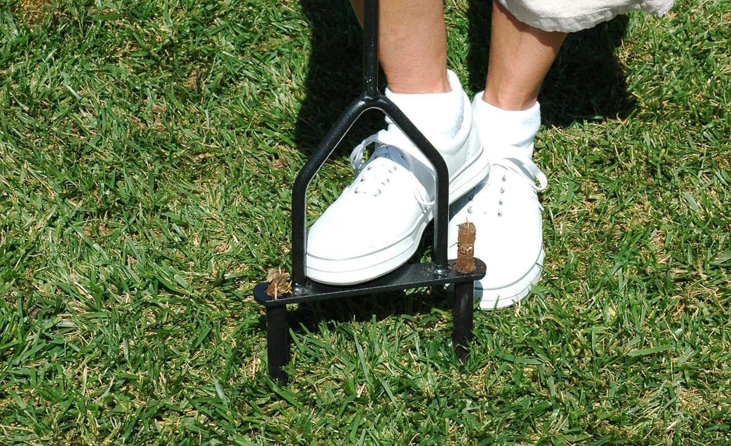 A person uses an aerator to aerate the soil in a yard. A person uses an aerator to aerate the soil in a yard.