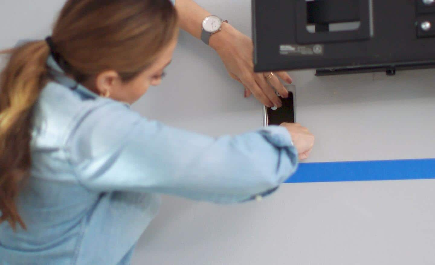 A woman installs a low voltage box into a wall.