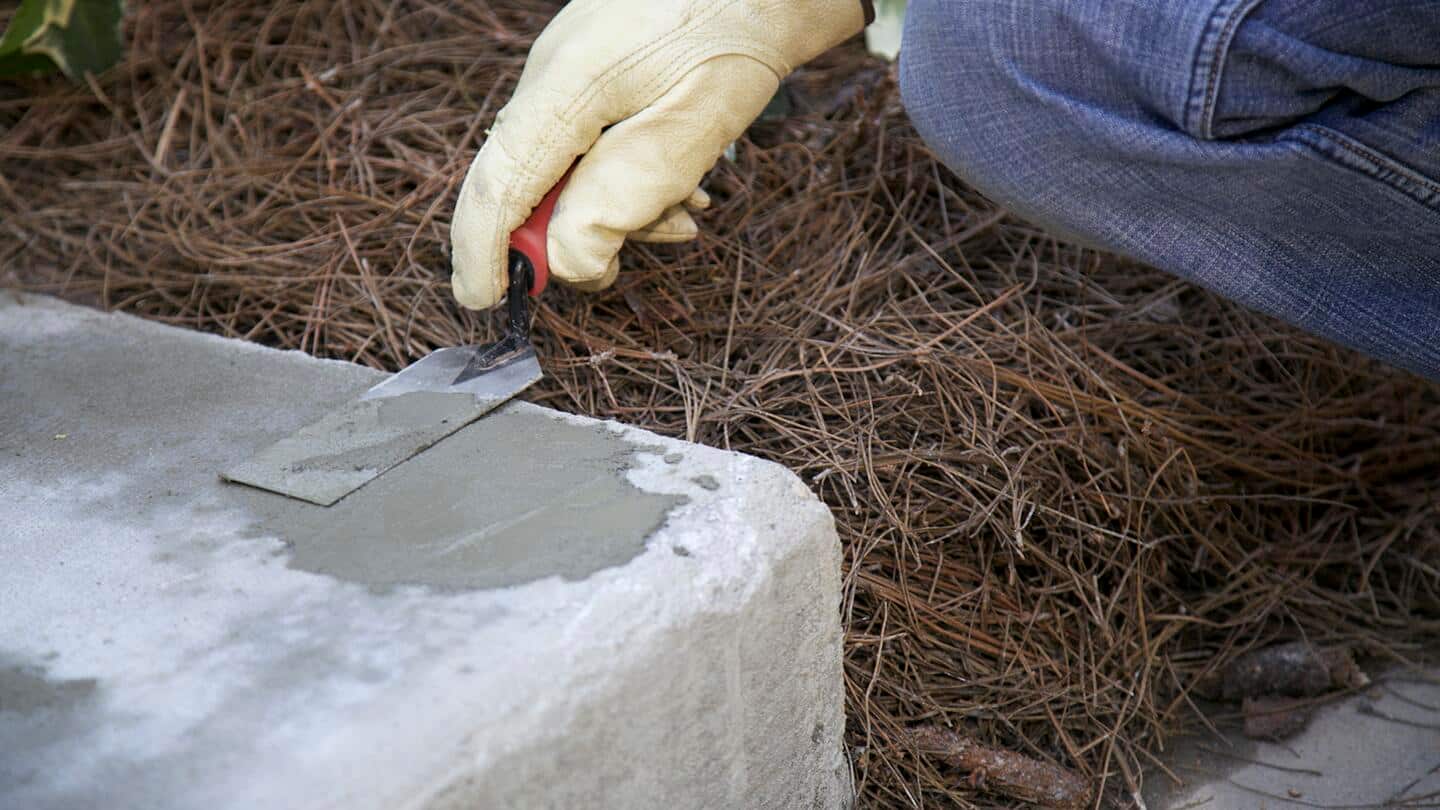 A person smooths a repair patch on a concrete step with a putty knife. A person smooths a repair patch on a concrete step with a putty knife.