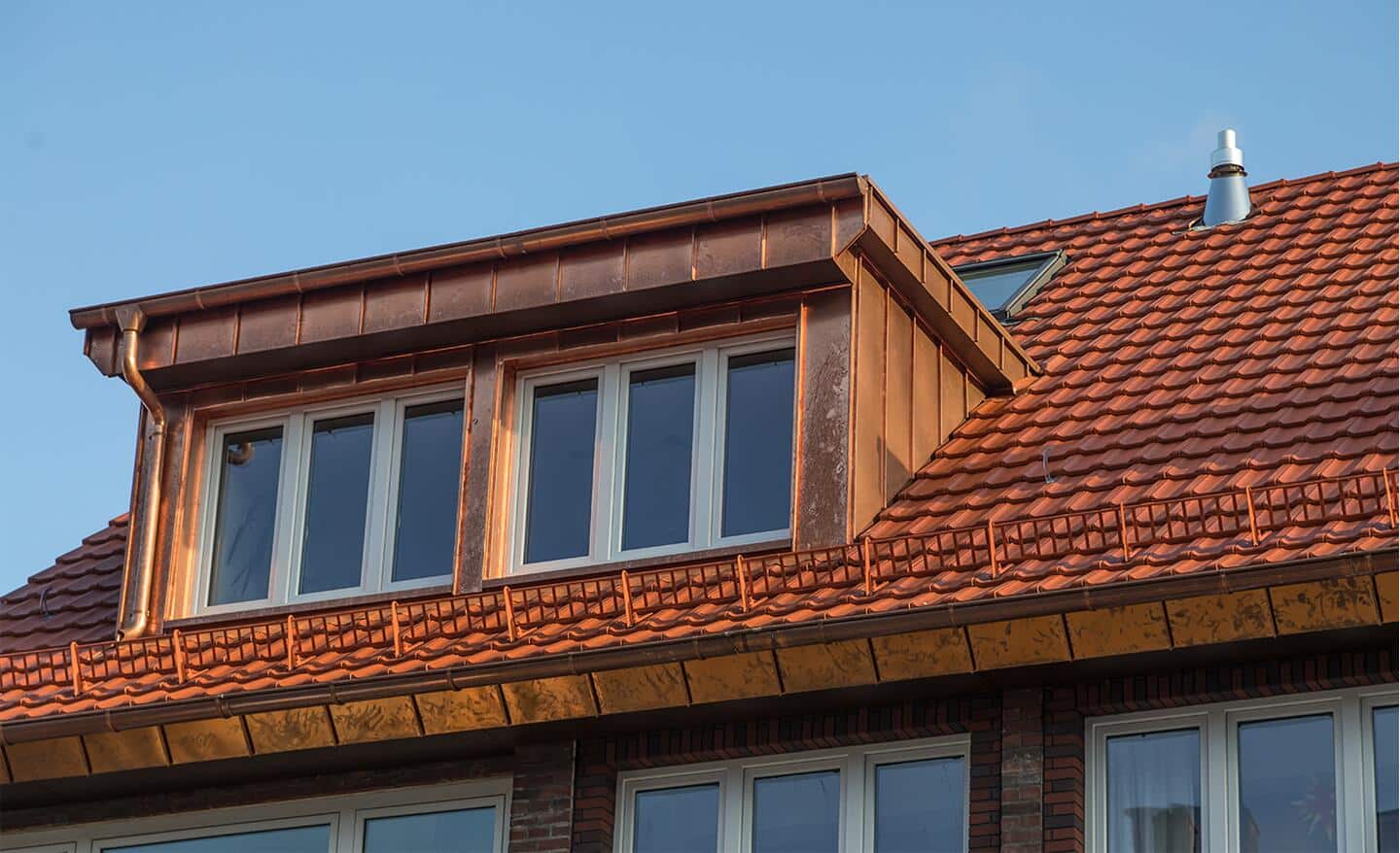 A home features a copper roof and attic windows.
