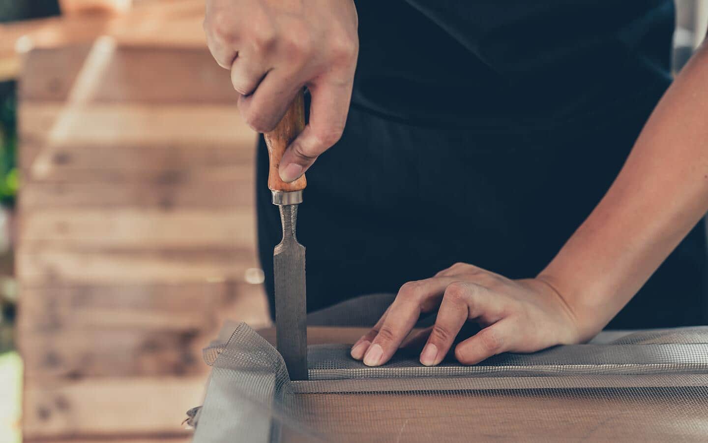 A person cutting new screen fabric. A person cutting new screen fabric.