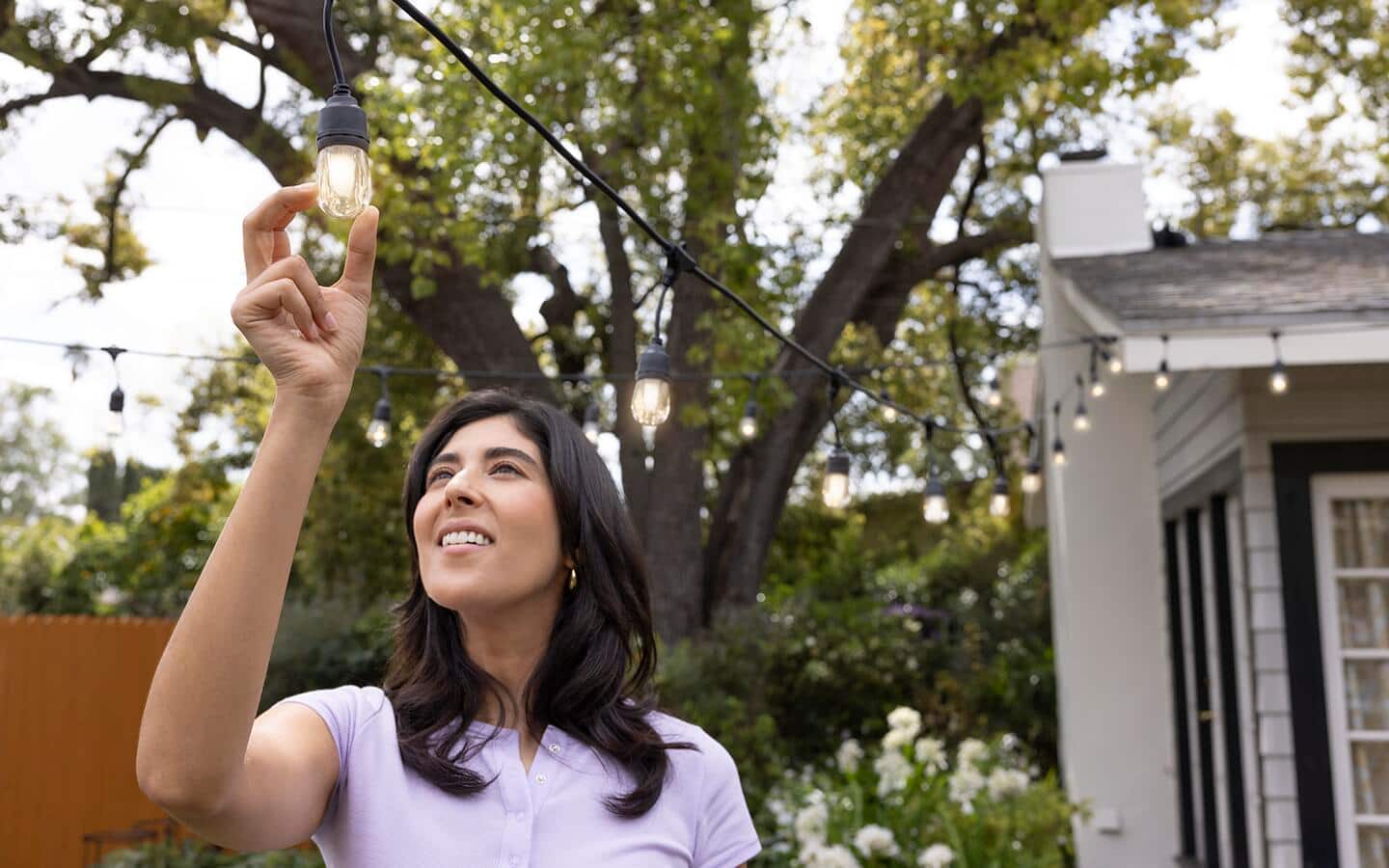 Someone hanging outdoor lighting in the backyard. Someone hanging outdoor lighting in the backyard.
