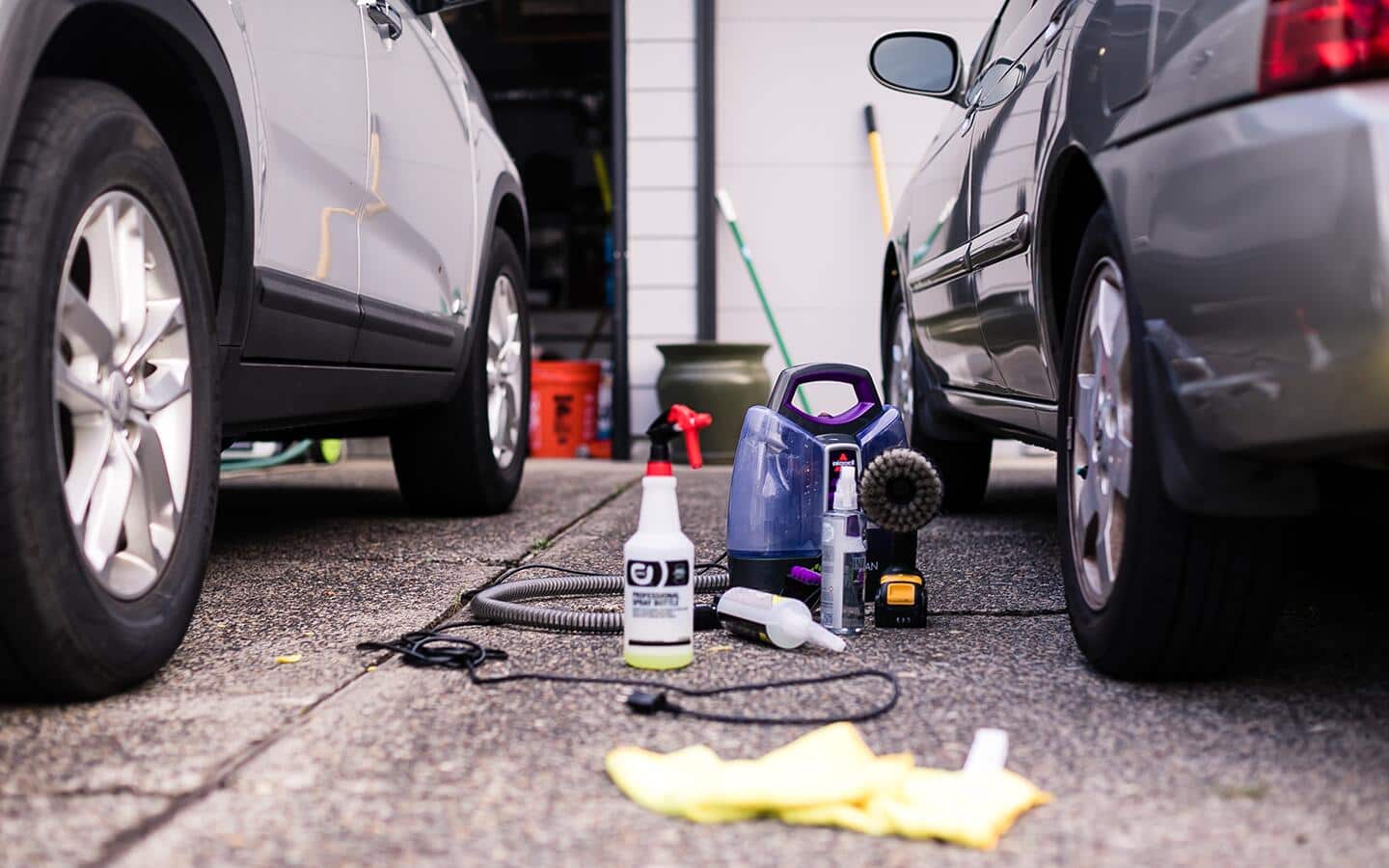 Car detailing supplies sit between the rear tires of two vehicles parked side by side.