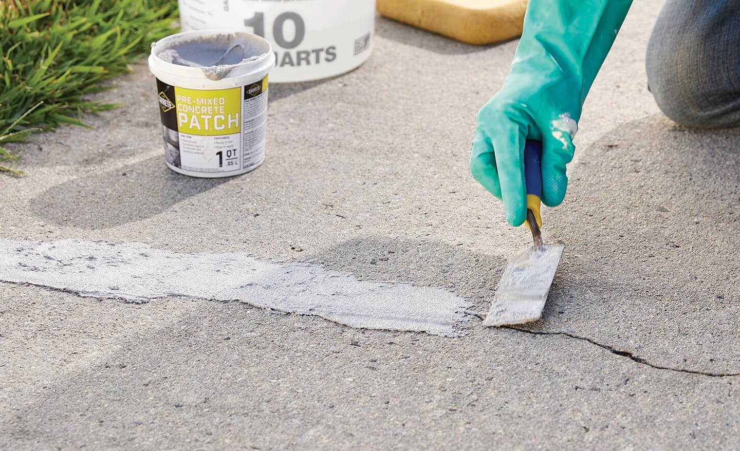 Using a trowel, a person smooths repair mix over a crack.