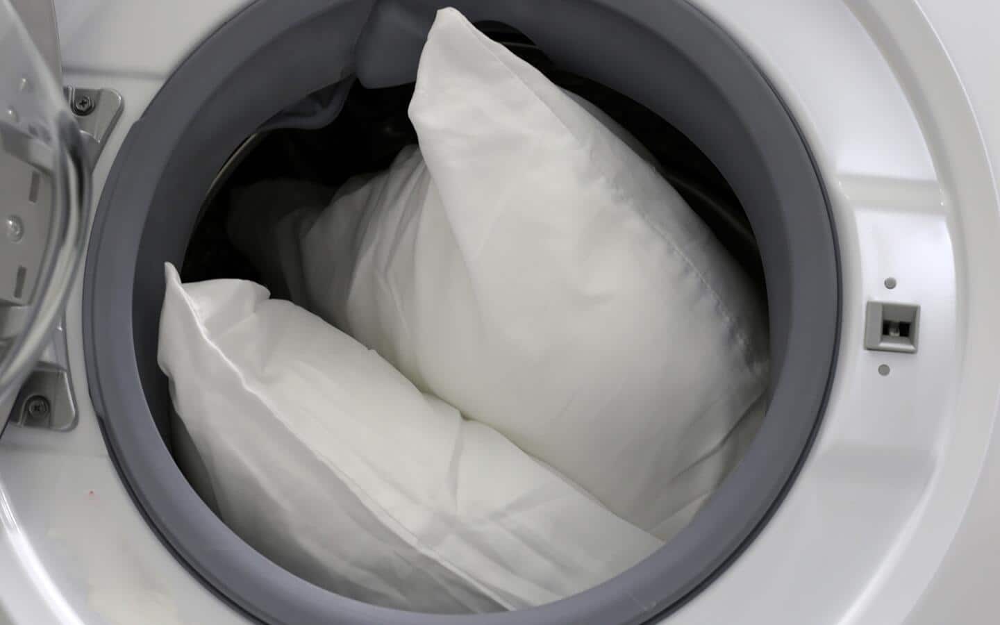 Pillows placed inside a washer. Pillows placed inside a washer.