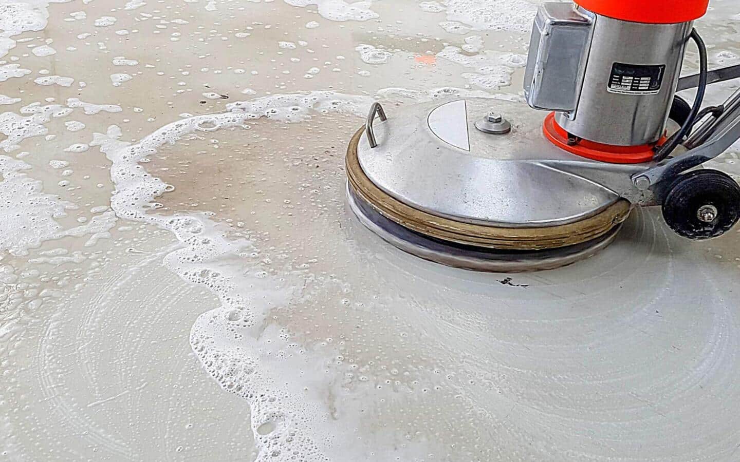 An electric floor scrubber cleans a concrete floor.