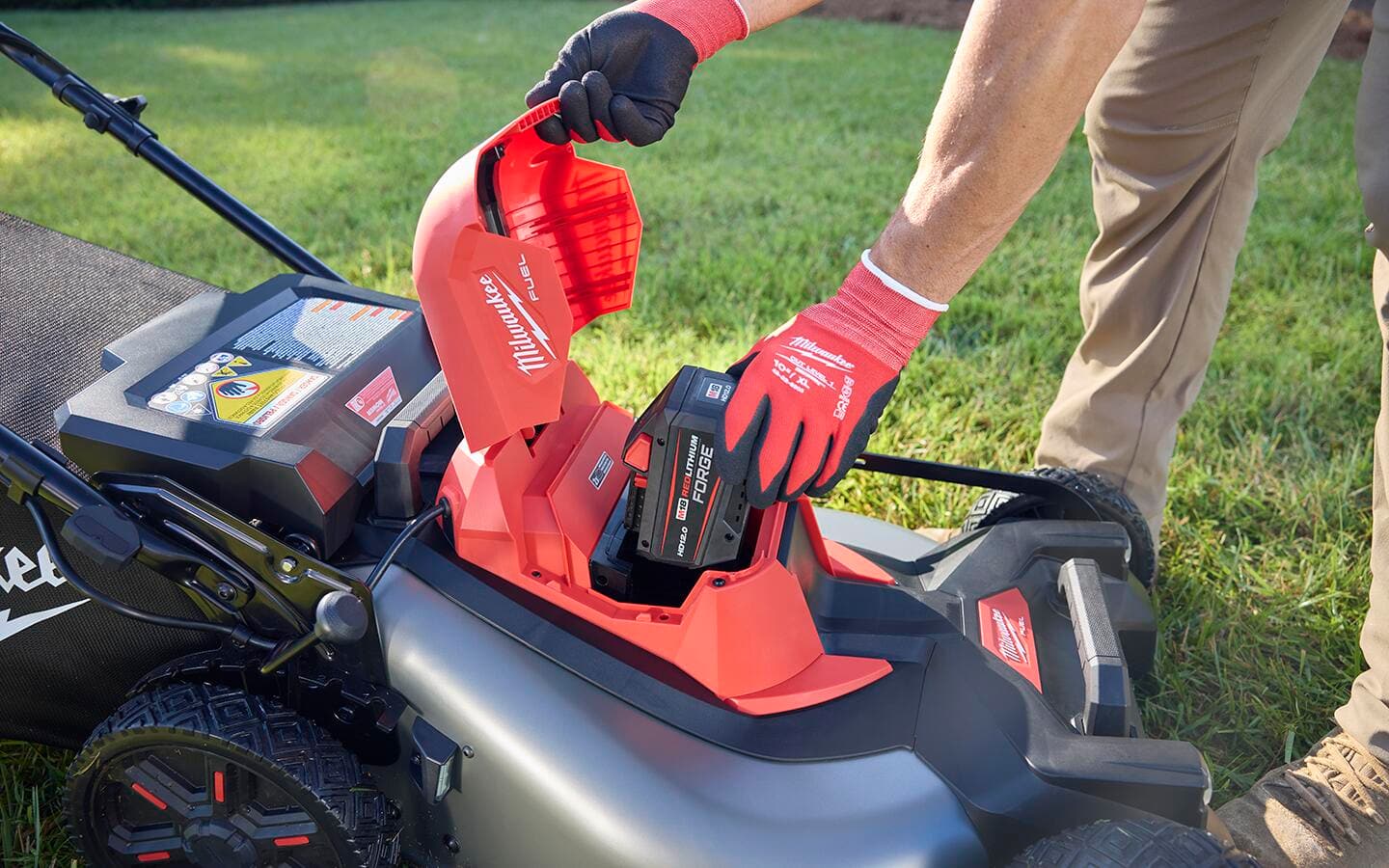 A person reinstalls a lawn mower battery.