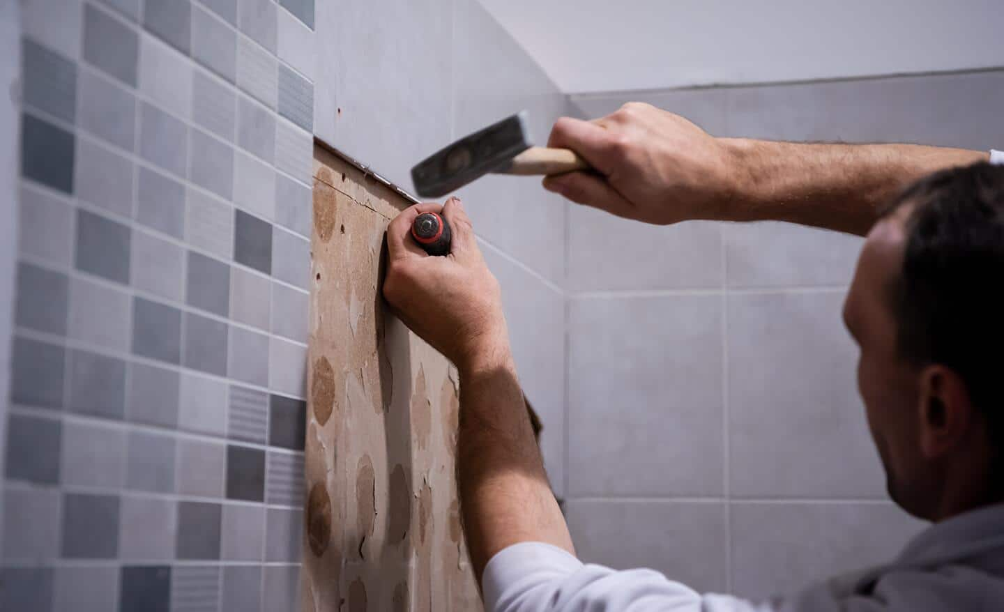 Someone removing tile from a wall.