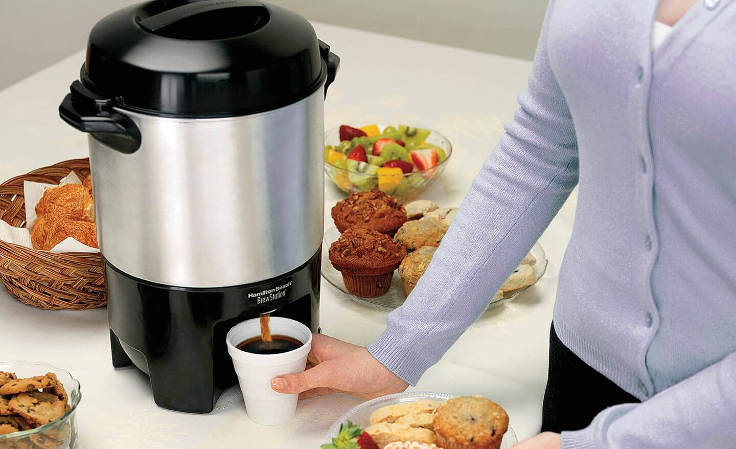 A person gets coffee from a coffee urn. A person gets coffee from a coffee urn.