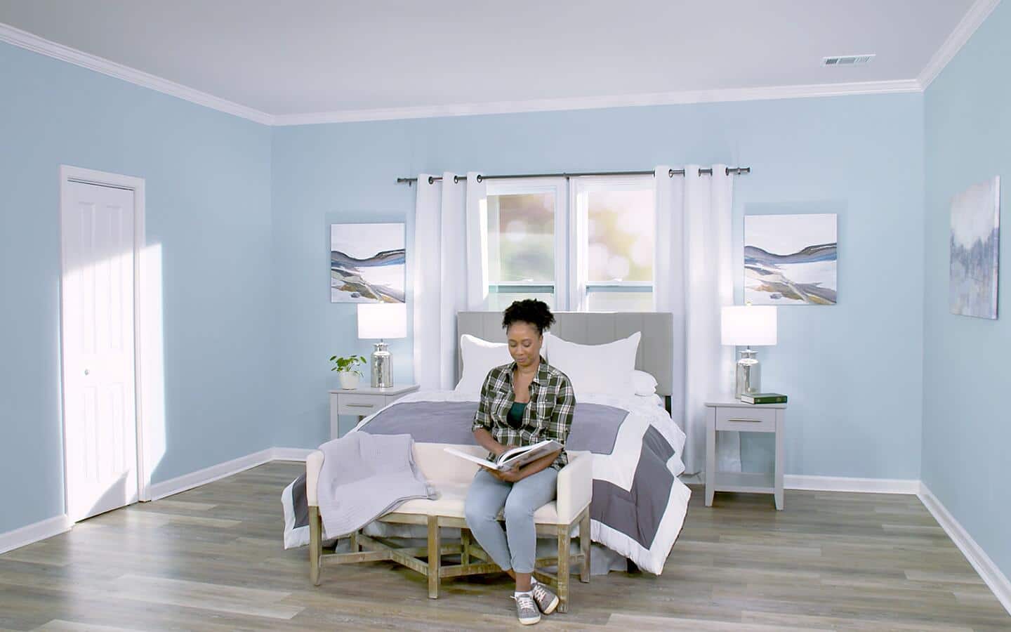 A person sits on a bed reading a book in a room with a painted ceiling. A person sits on a bed reading a book in a room with a painted ceiling.