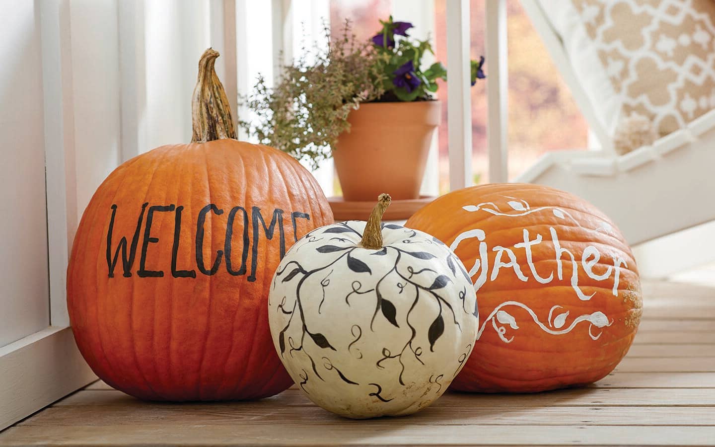 Pumpkins painted and decorated with sayings and vines.