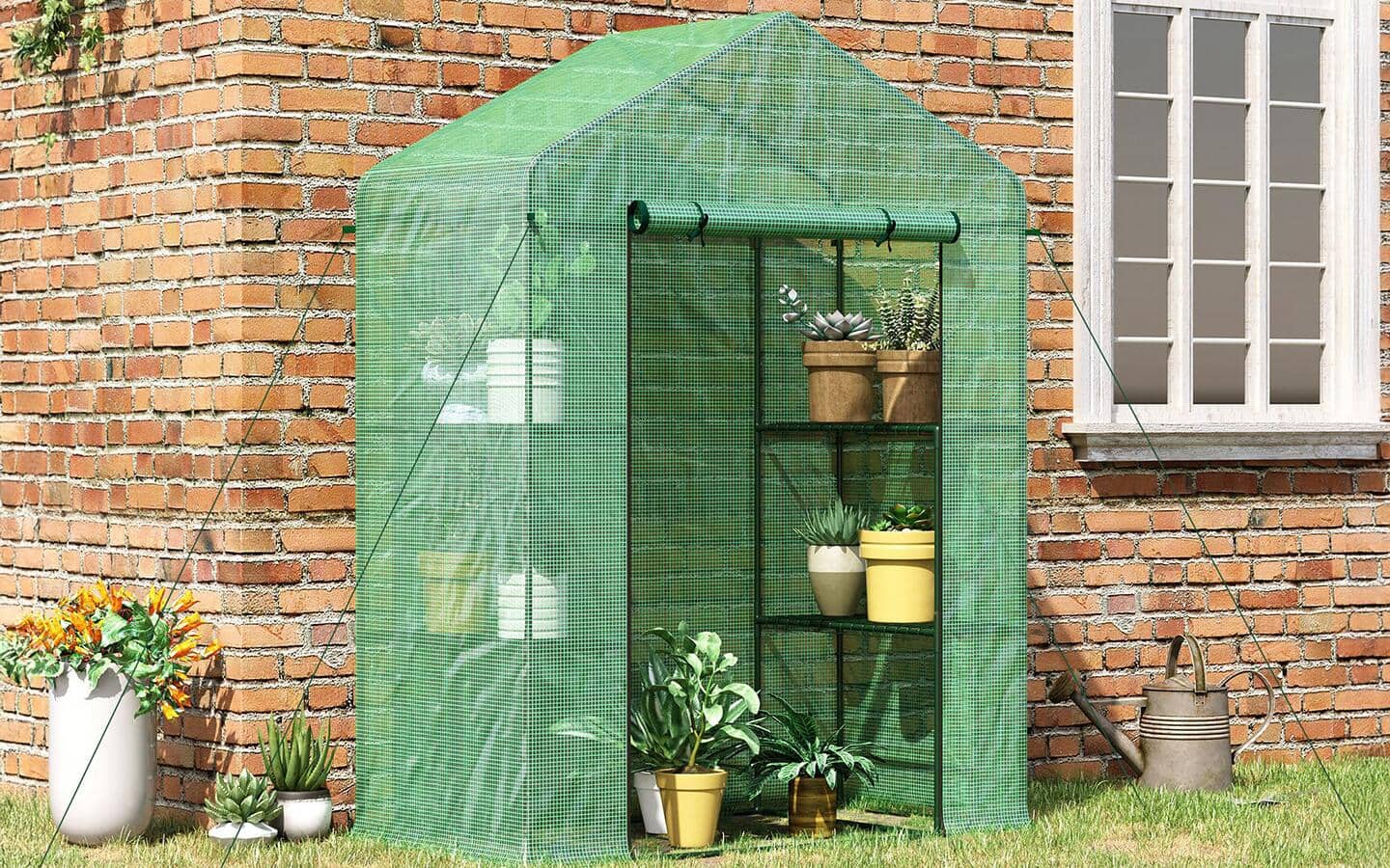 A portable greenhouse filled with potted plants next to a brick house