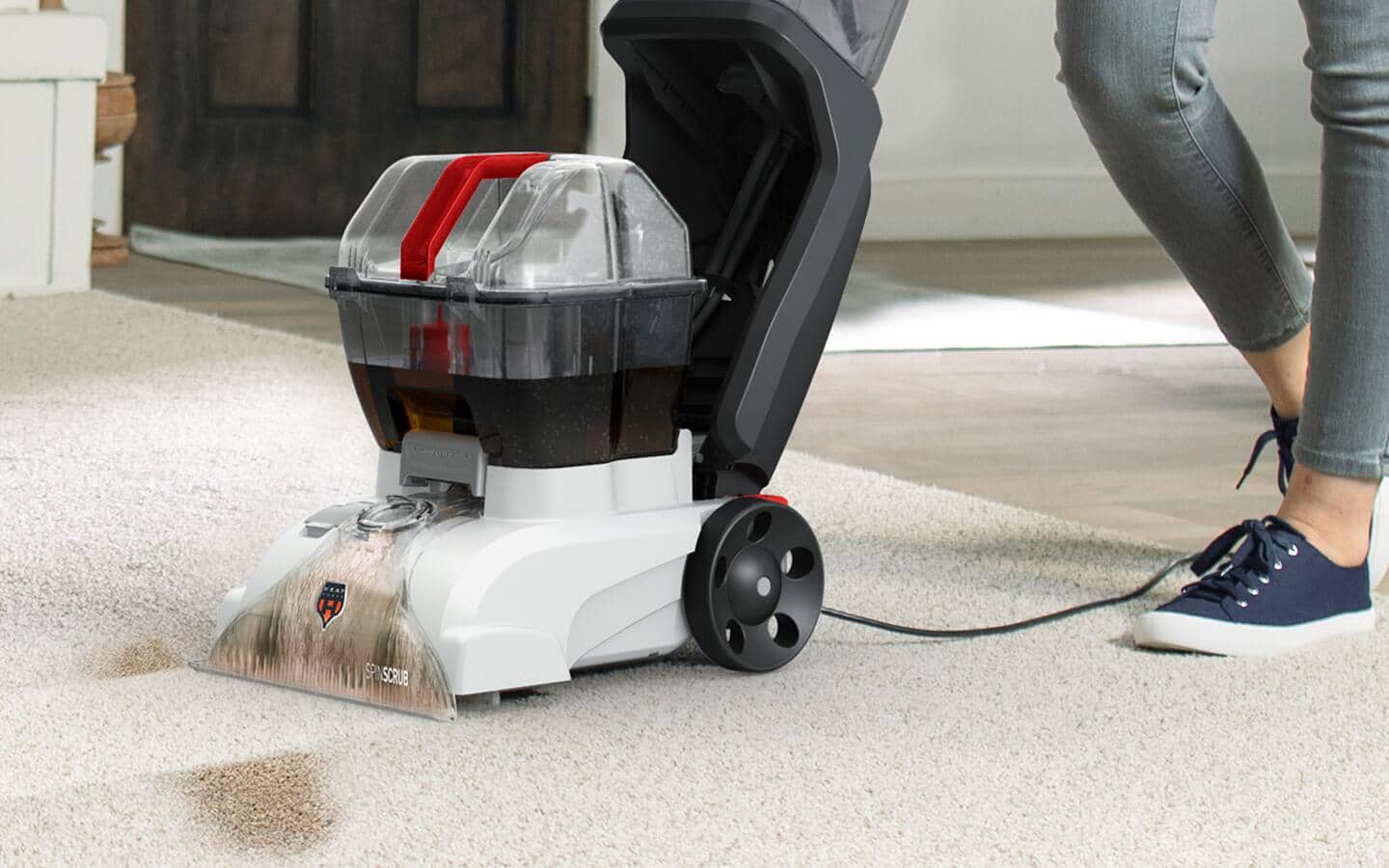 Someone using a carpet shampooer on a white rug. Someone using a carpet shampooer on a white rug.