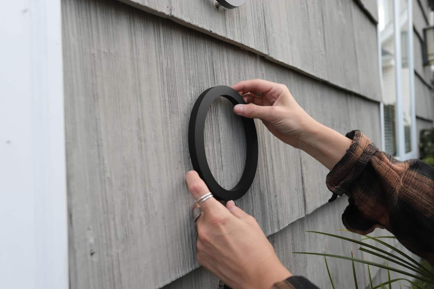 A person holding up a house number.