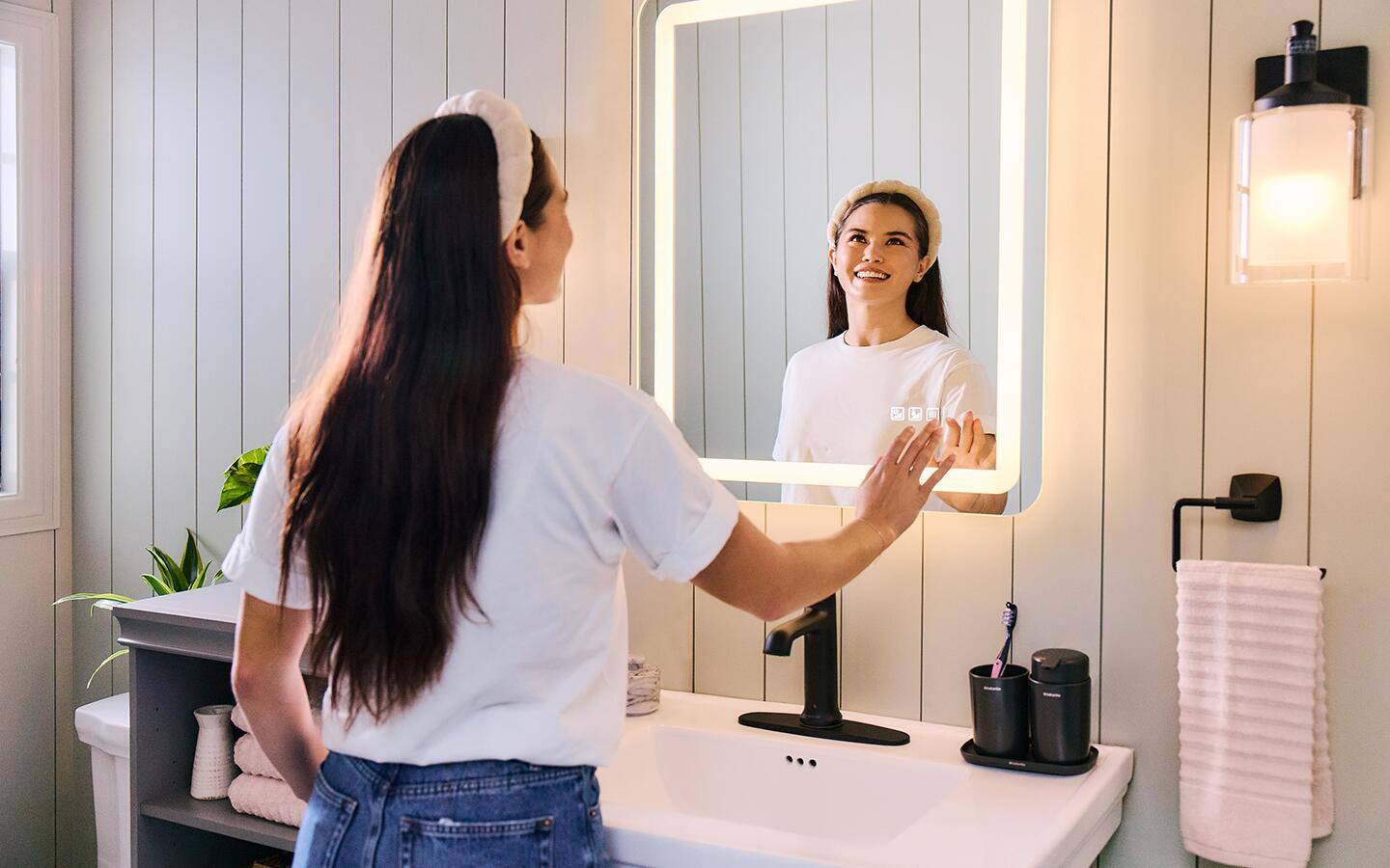 A woman lights up a smart mirror with a touch of her hand