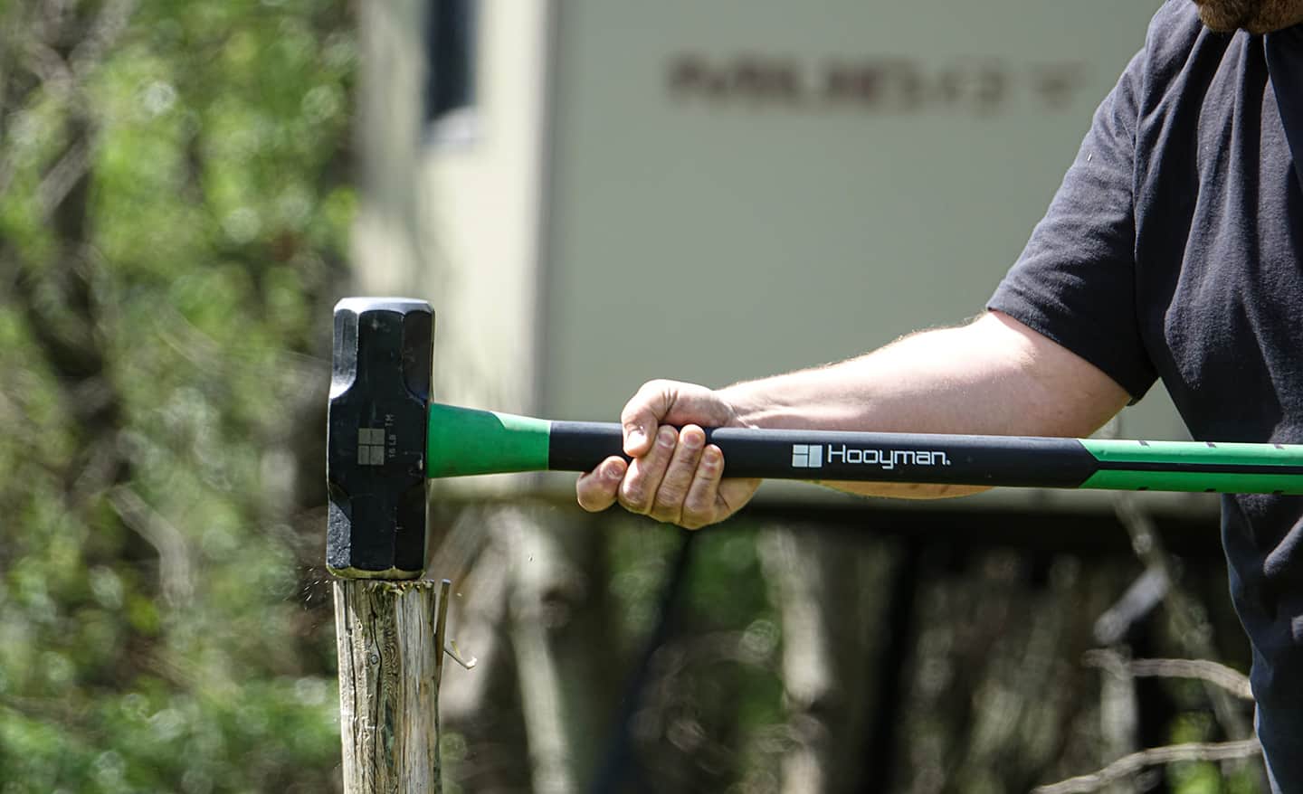 A person uses a striking tool to drive a post.