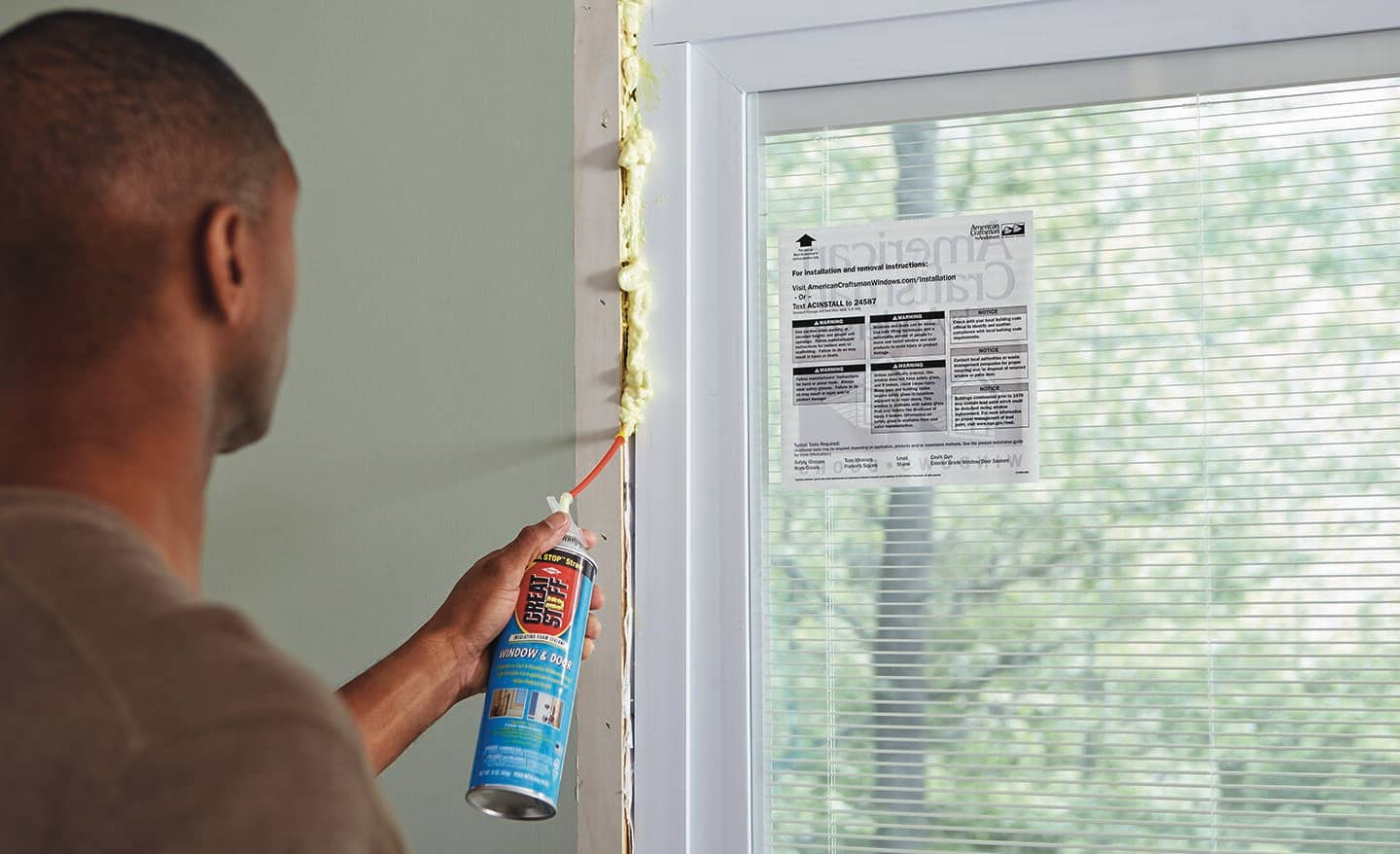 Someone uses expandable foam to fill the gaps along a newly installed sliding door.