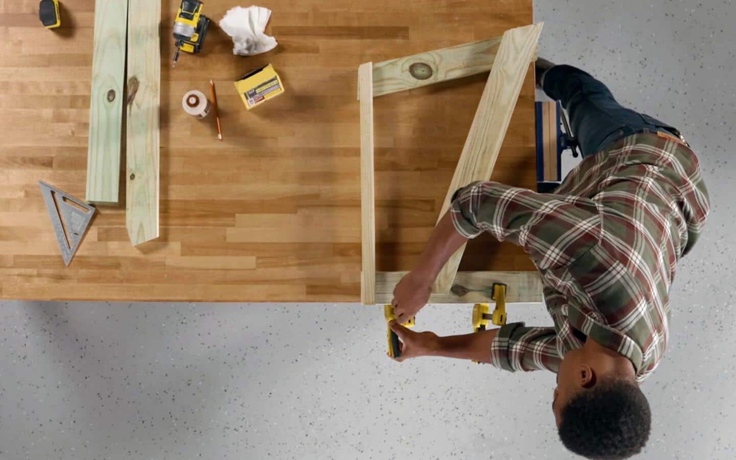 An individual attaches a stringer board to the front and back legs of a sofa being built. An individual attaches a stringer board to the front and back legs of a sofa being built.