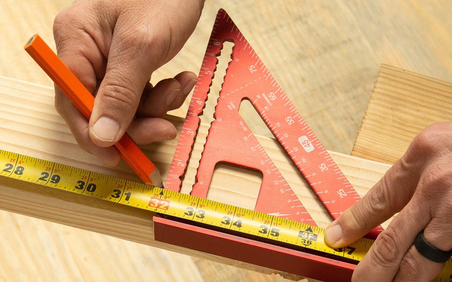 A person marking a crosscut with measuring tape and a layout square. A person marking a crosscut with measuring tape and a layout square.