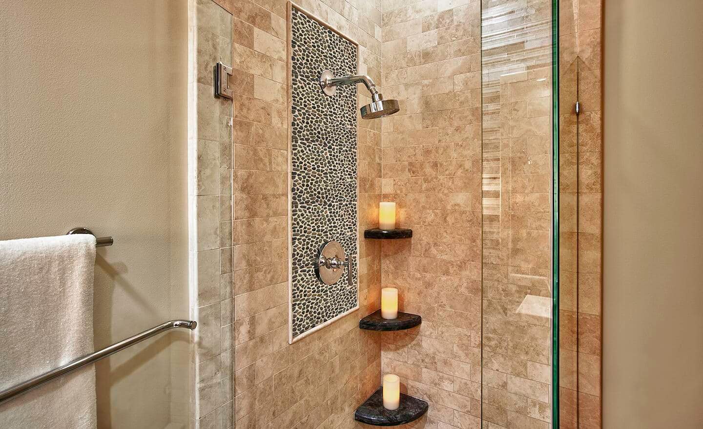 A small shower featuring a mix of smooth and pebbled tiles.