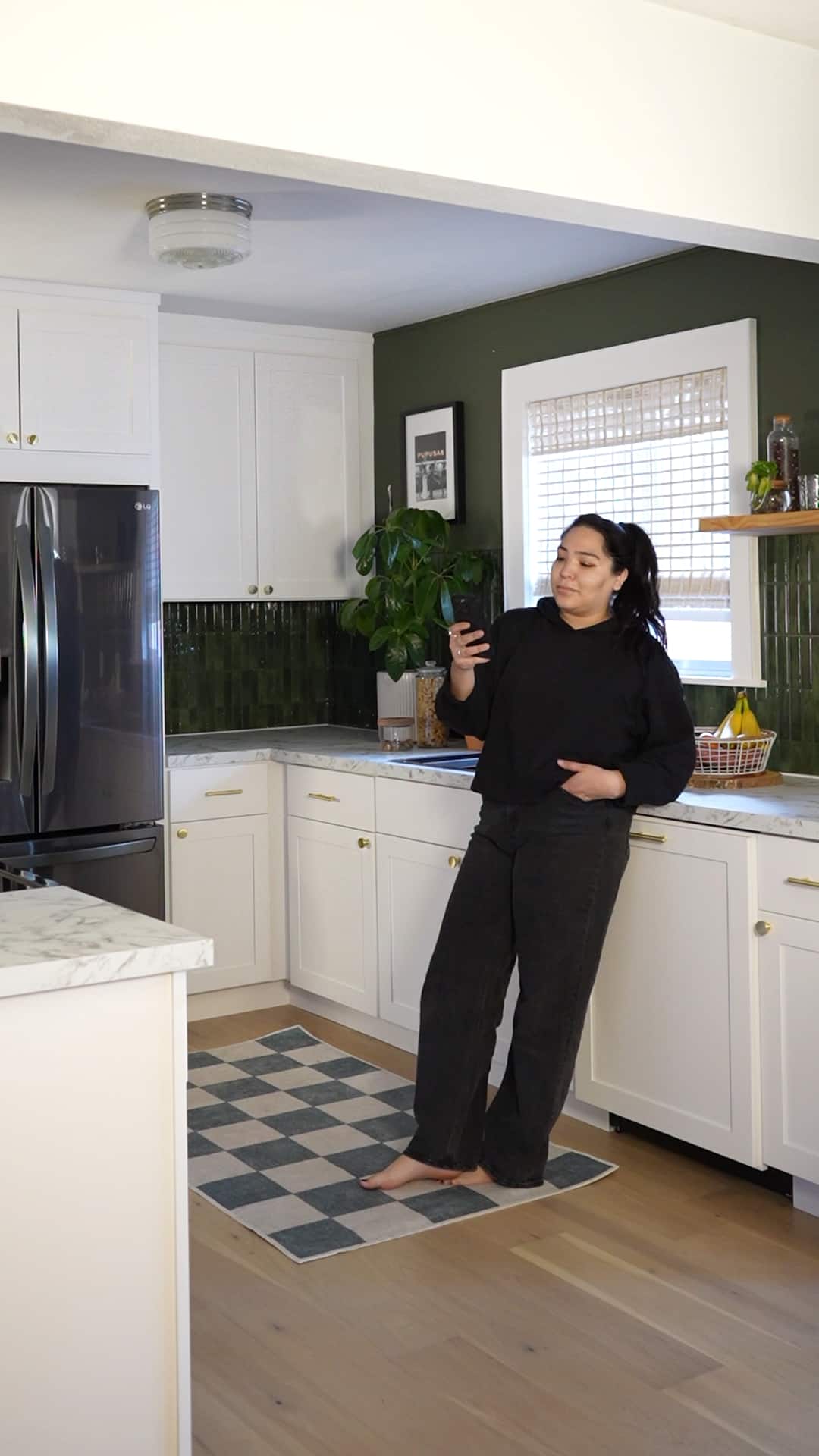 Vanessa scrolls on her phone in the beautiful and calming space that is her updated kitchen.