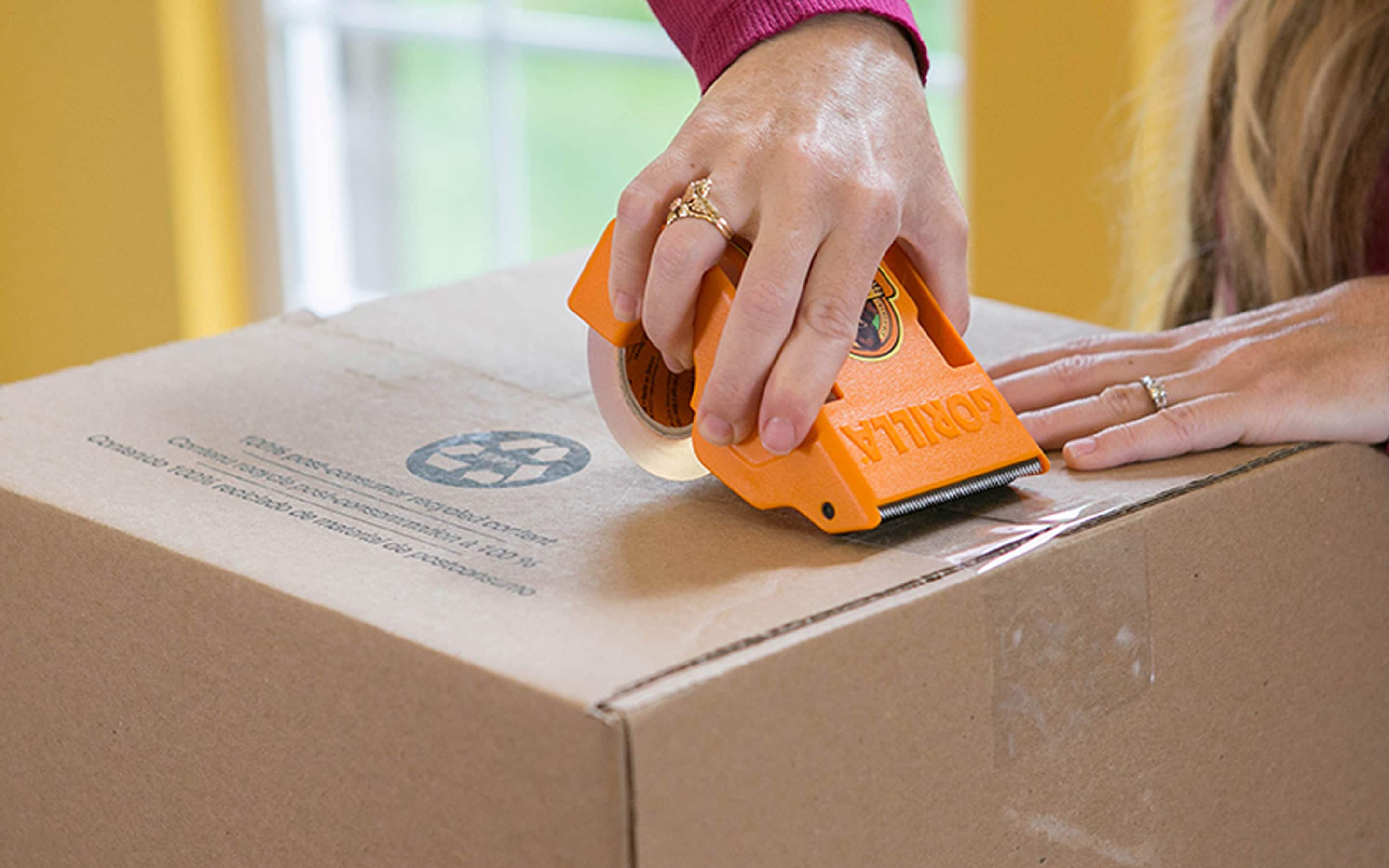 A person uses packing tape to seal a box. A person uses packing tape to seal a box.
