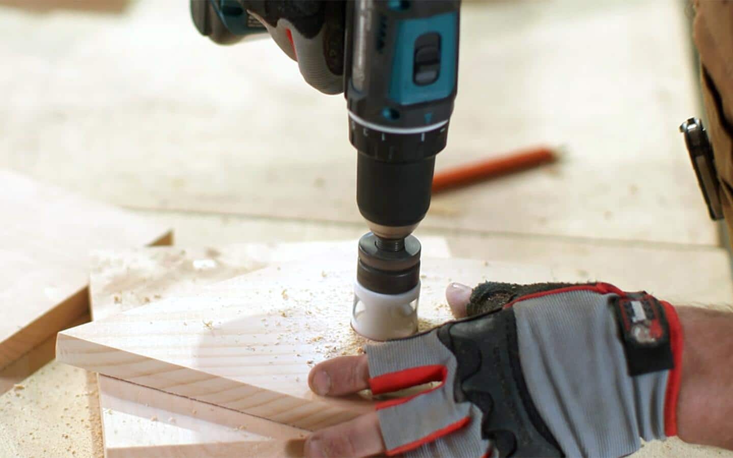 An individual uses a drill fitted with a hole saw to make a birdhouse's entrance.