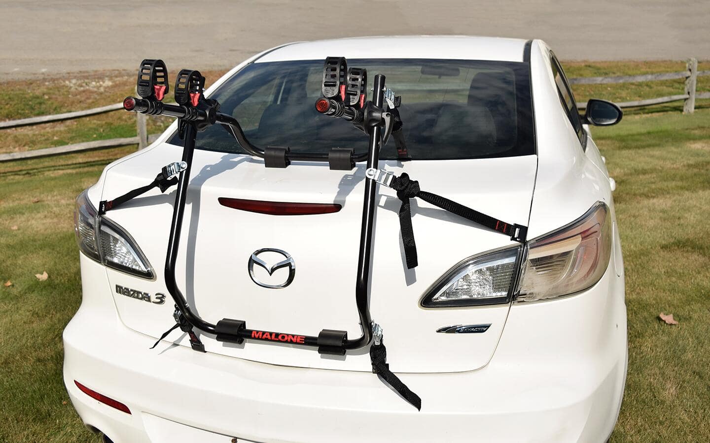 A white car features a trunk-mounted bike rack.
