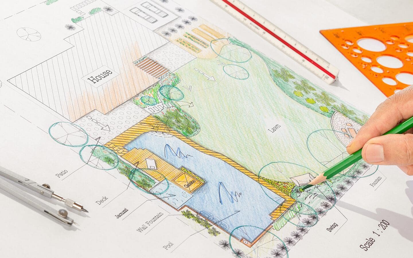 Someone working on a colored pencil drawing of a garden plan.