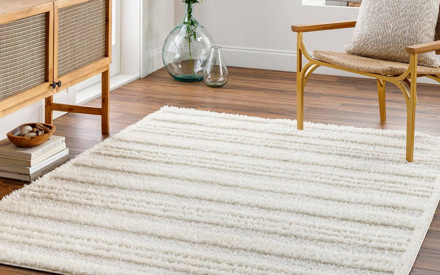 A high-low rug in shades of beige lays in front of a credenza in a living room.