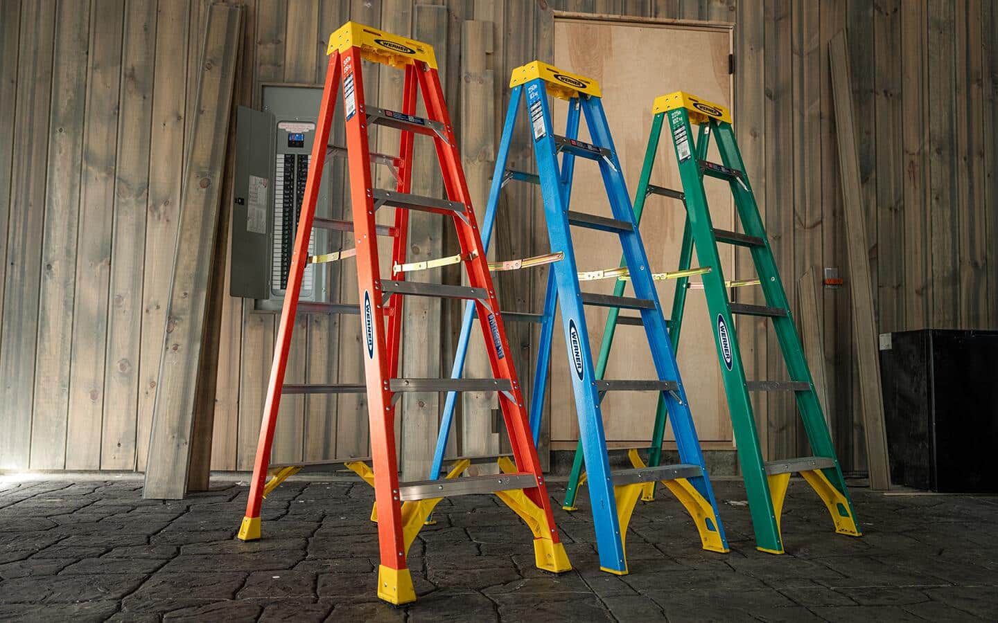 Three stepladders in different colors, orange, blue, and green.