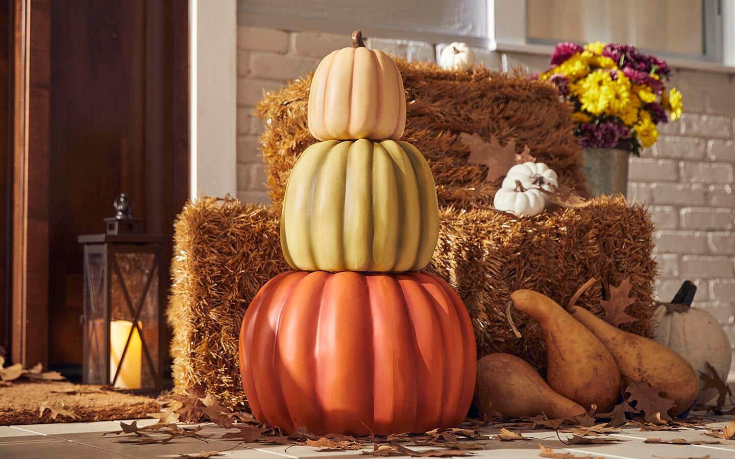 A tower of pumpkins next to bales of hay on a porch. A tower of pumpkins next to bales of hay on a porch.