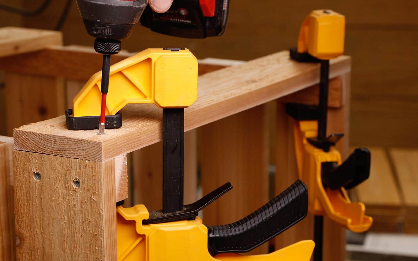 Yellow clamps holding the sides of DIY compost bin together.