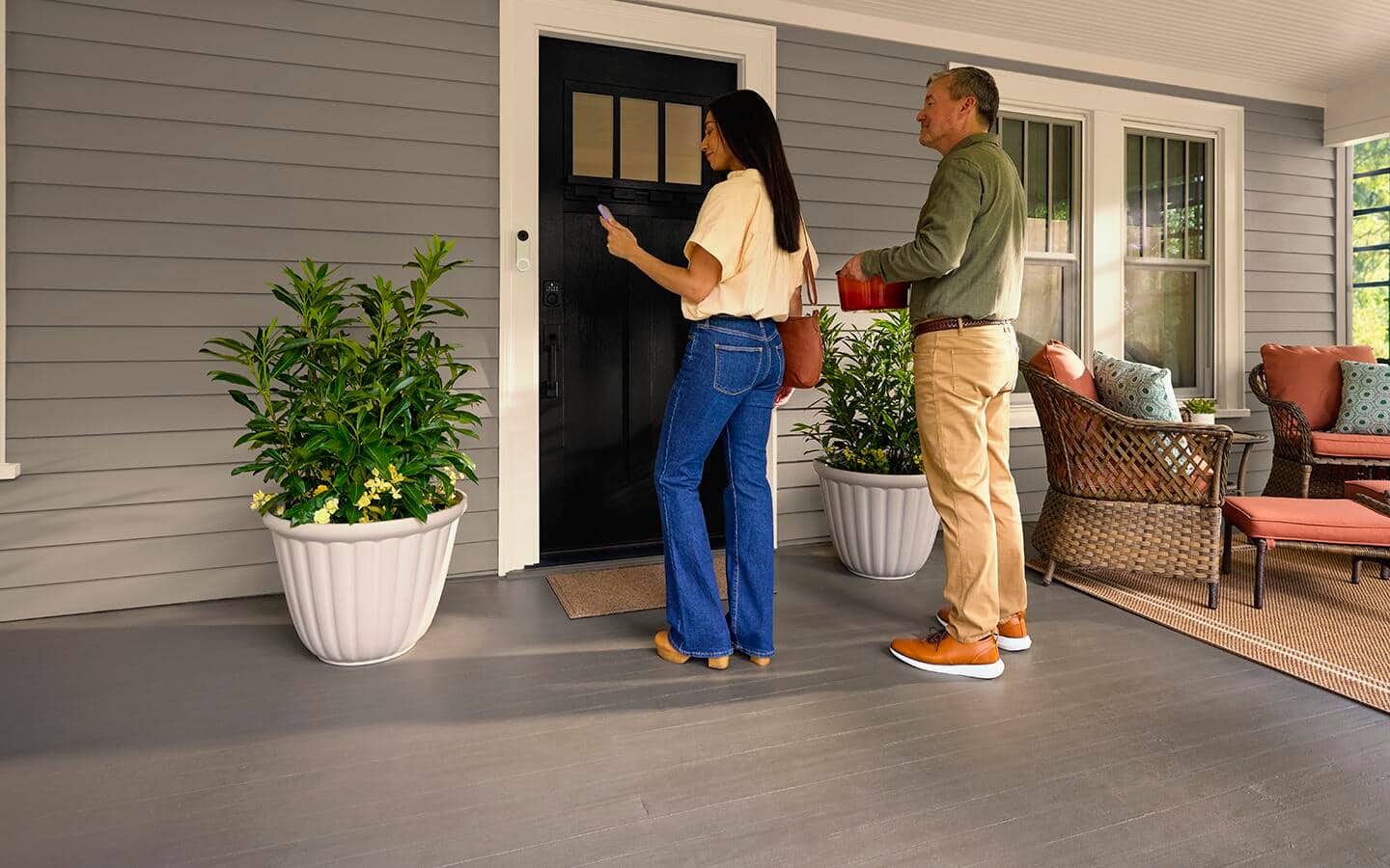Two people facing a camera doorbell at a front door.