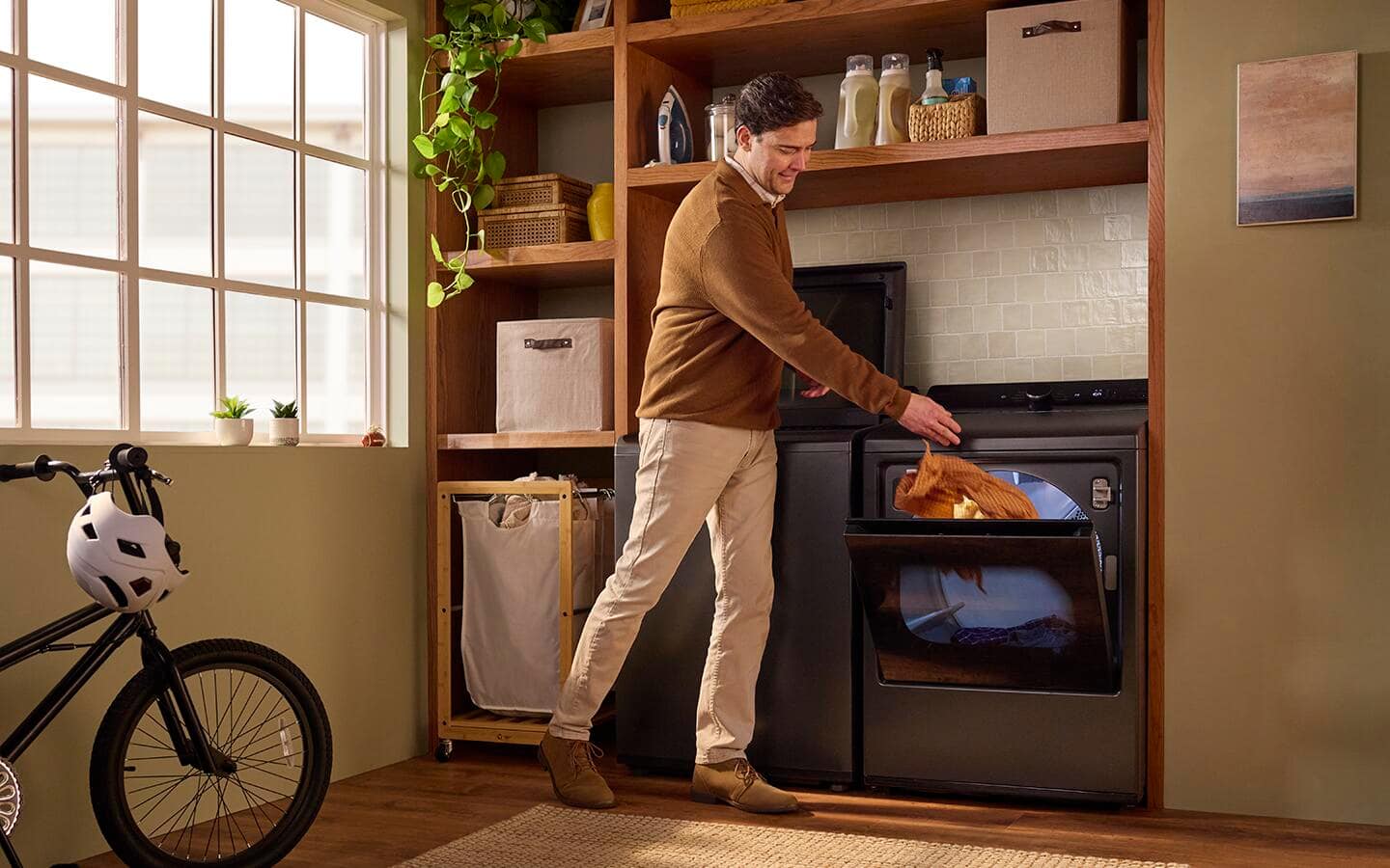 An individual placing an orange article of clothing into a smart dryer. An individual placing an orange article of clothing into a smart dryer.