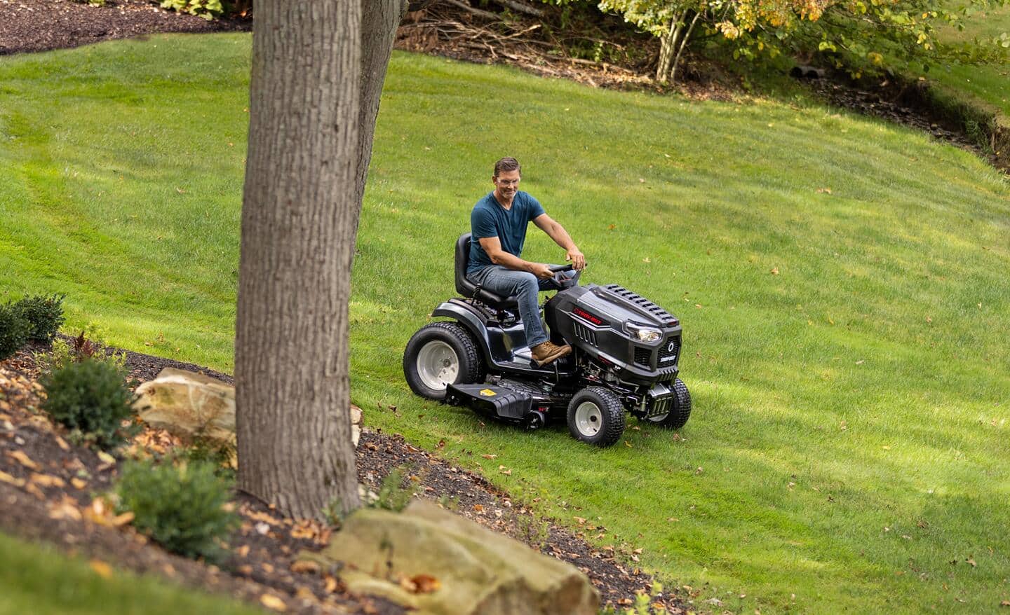 A man on a riding lawn mower mows a healthy green lawn