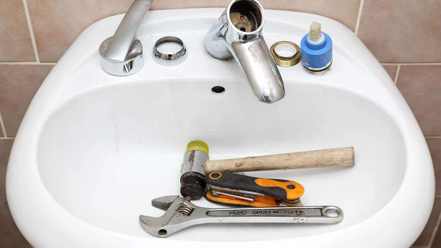 A disassembled sink with tools in the basin. A disassembled sink with tools in the basin.