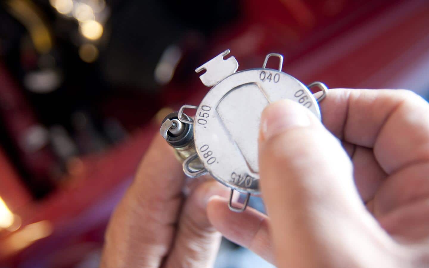 A person uses a spark plug gauge.