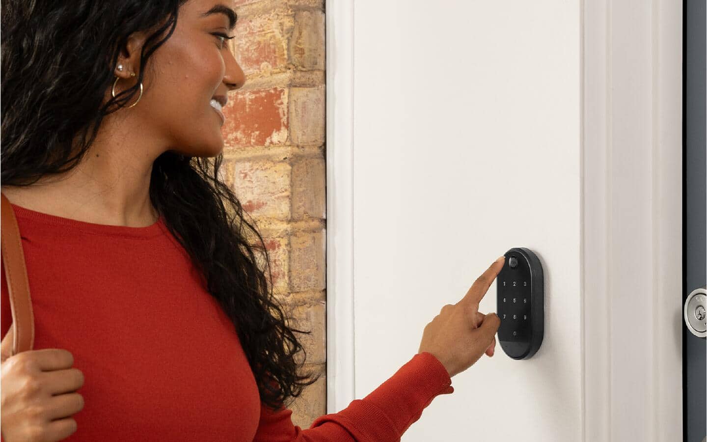 A person punches in the code for a smart lock using a keypad. A person punches in the code for a smart lock using a keypad.