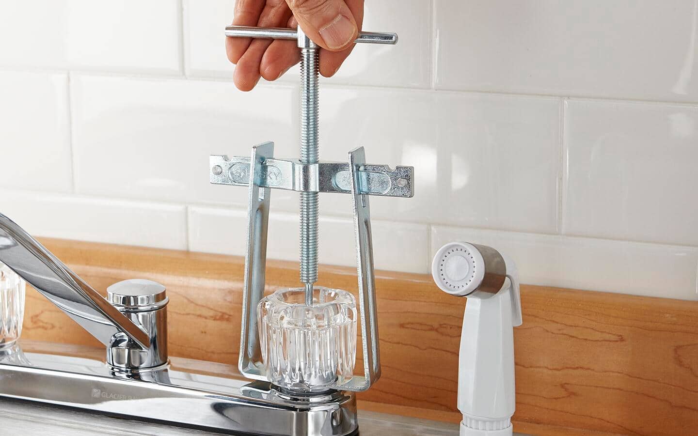 Person removing the faucet knob. Person removing the faucet knob.