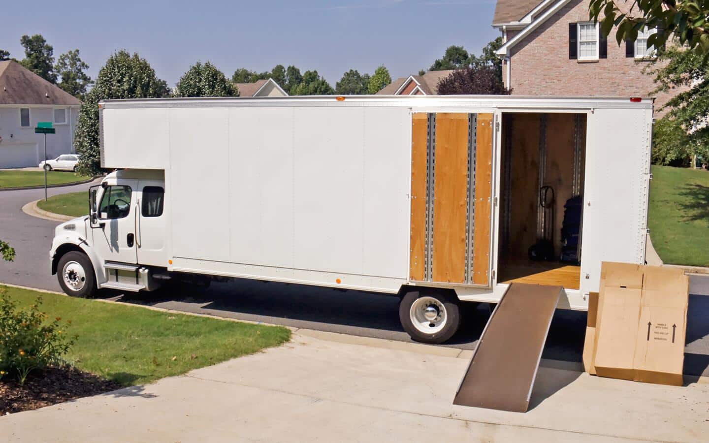 A moving truck in front of a driveway. 