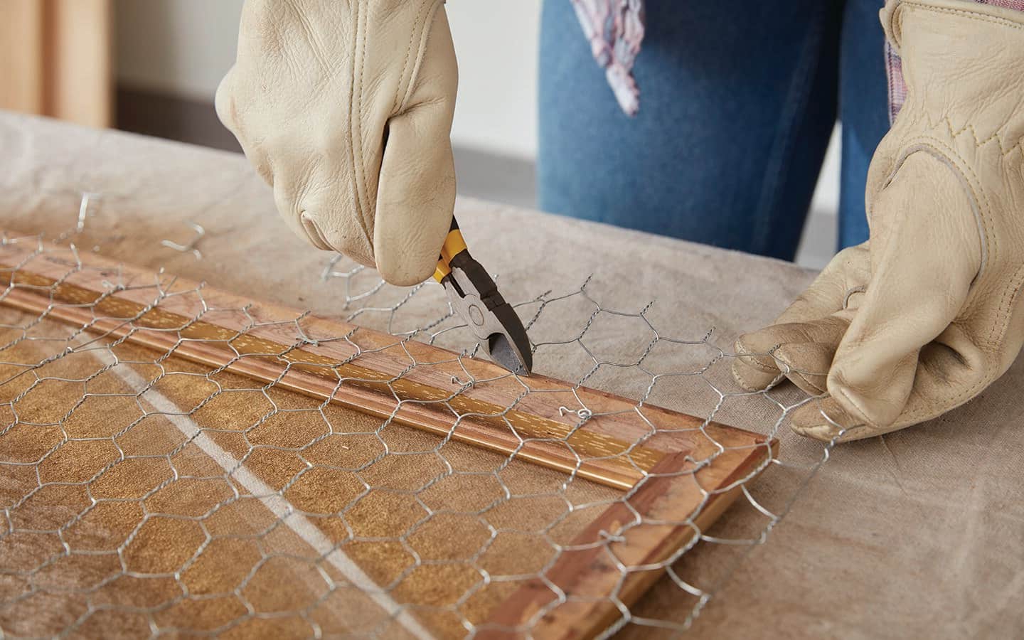 A person trims chicken wire by the edge of a frame. A person trims chicken wire by the edge of a frame.