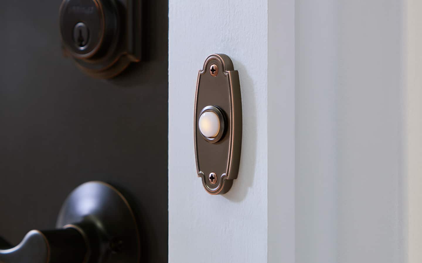An ornate, metallic wired doorbell next to a front door handle. An ornate, metallic wired doorbell next to a front door handle.