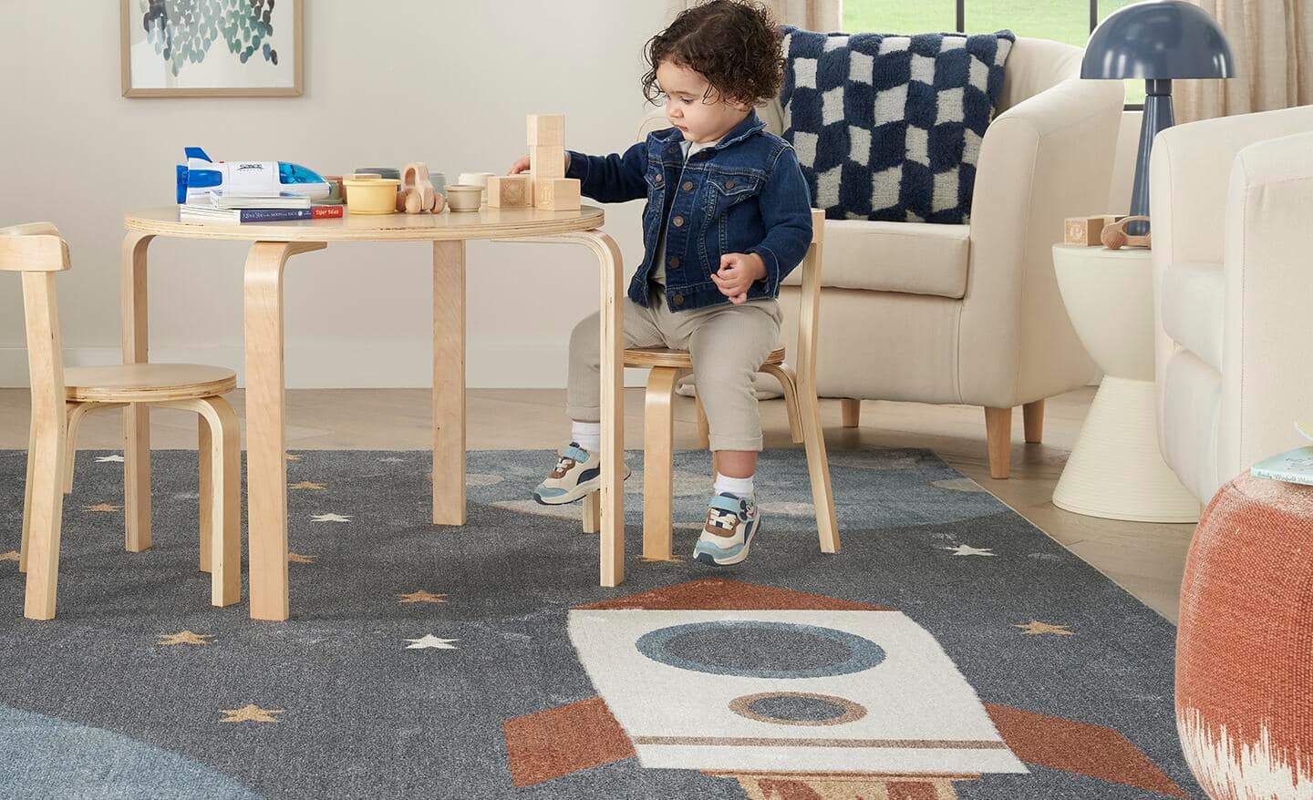 A child playing with blocks at a table placed on a washable rug. A child playing with blocks at a table placed on a washable rug.