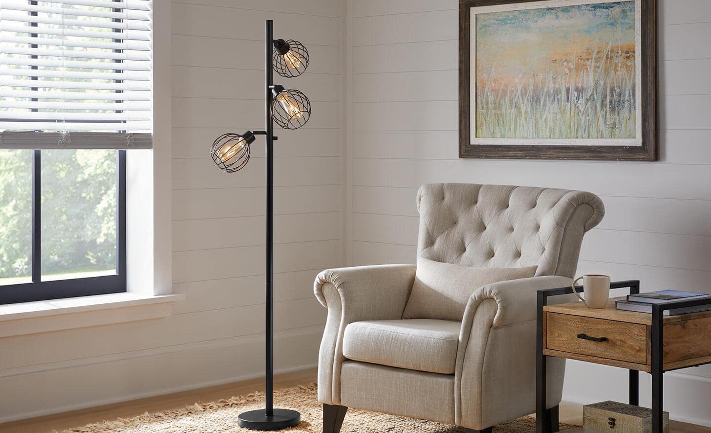 A tree floor lamp with three branches sits next to a white armchair.