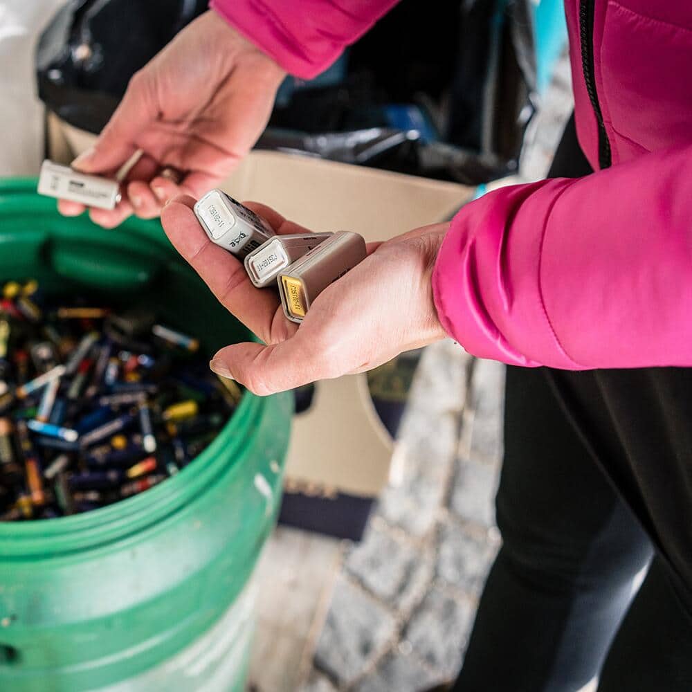 A person puts a battery inside a recycling box.