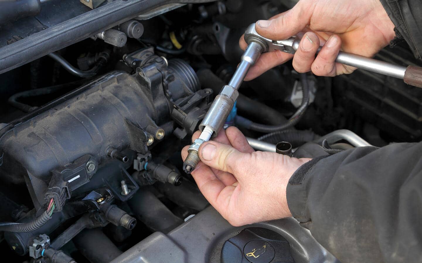 A person removes old spark plugs. 