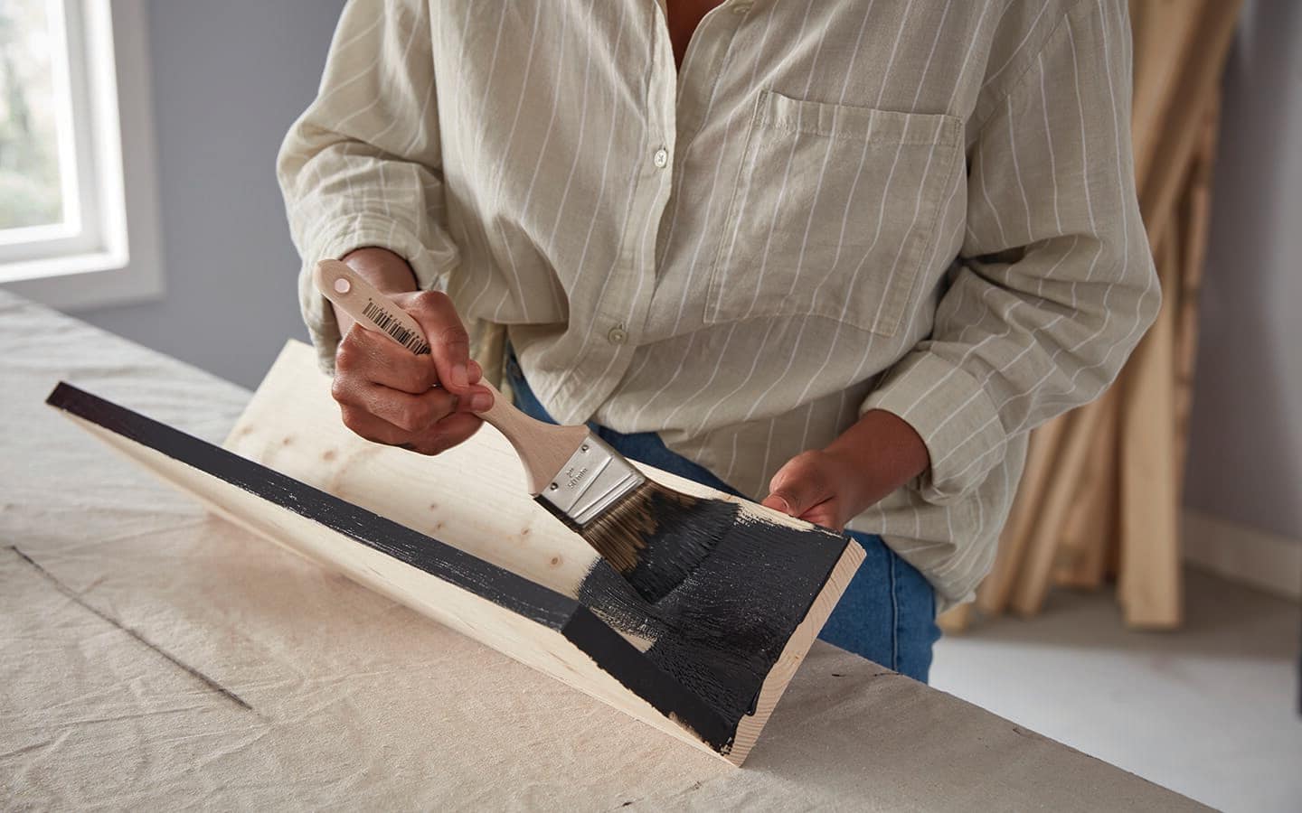A person paints a DIY coat rack hanger.