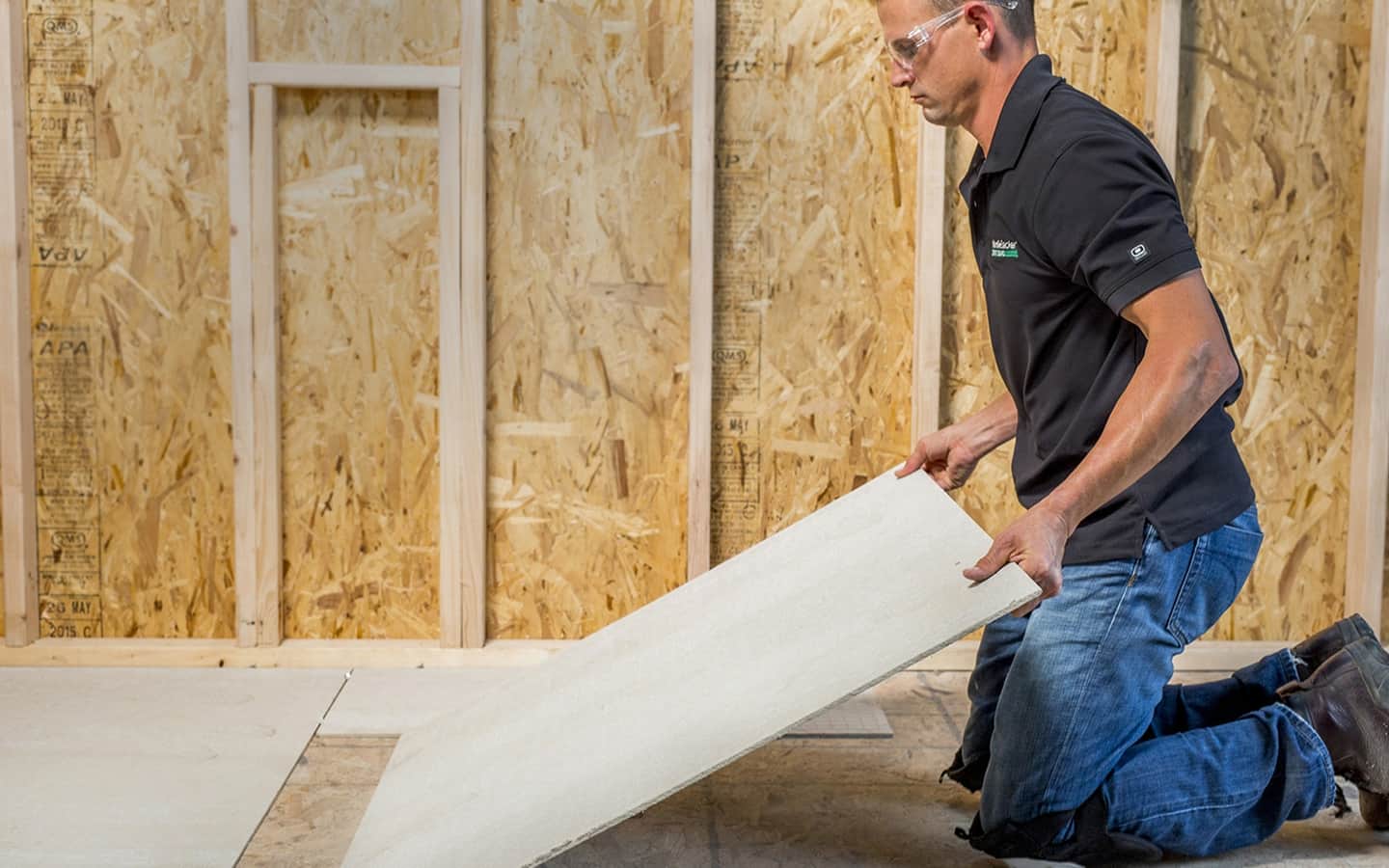A Pro positioning backer board on a subfloor.